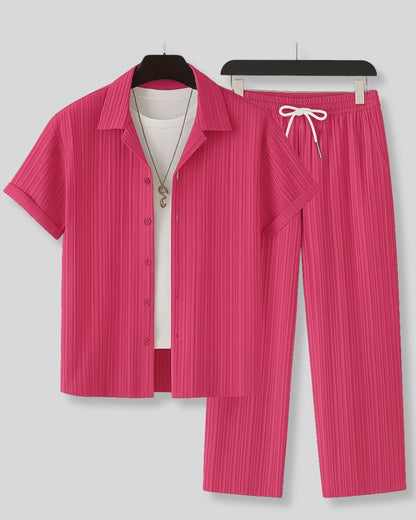 Pink pleated shirt and pants set on hangers against a gray background